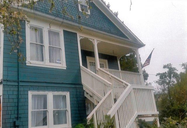 After: Completed view of the house front without trees and with repaired stairs and porch.